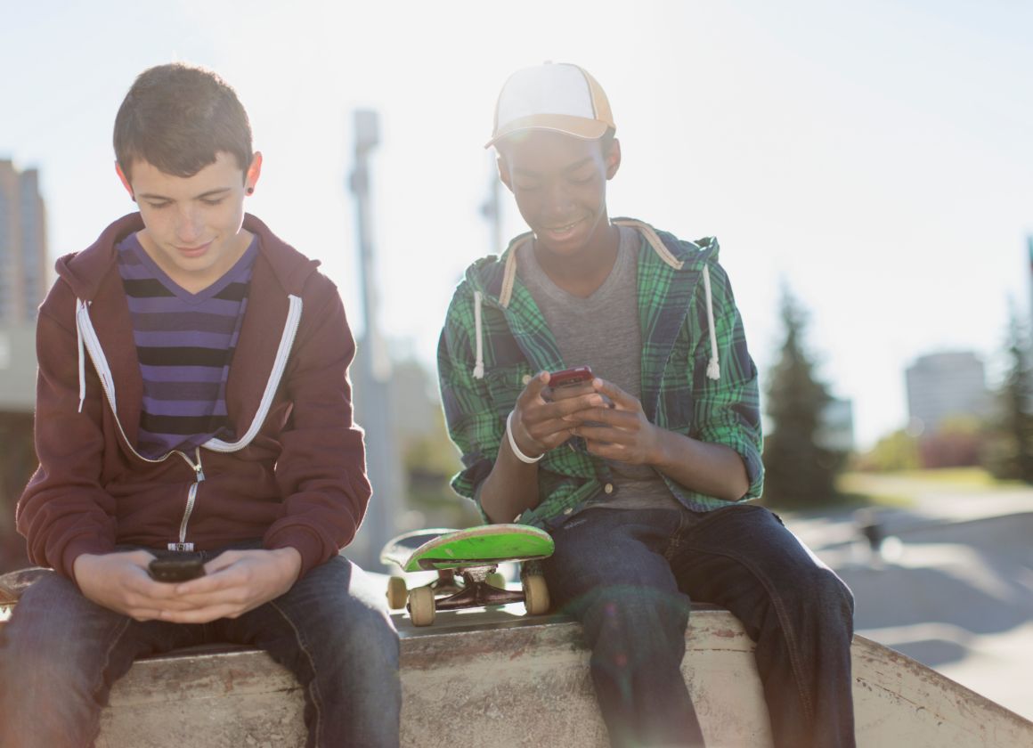 An image of two young people sitting outside and texting on a web page about Kids Help Phone’s mental health website