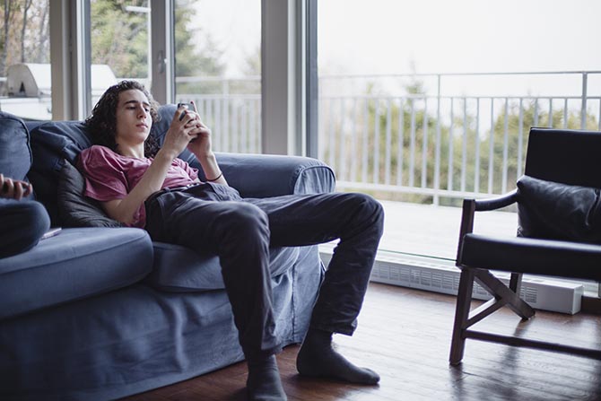 Young person sitting on a couch and using a phone